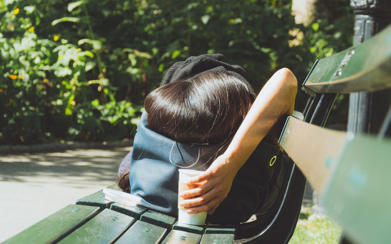 Woman sleeping on bench at park