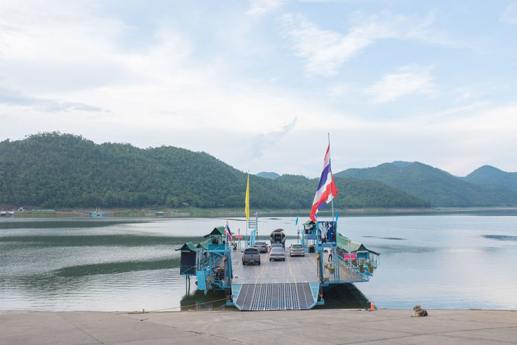 Thai flag on ferry with cars moored at lake