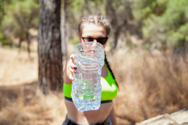 Woman holding water in bottle in forest