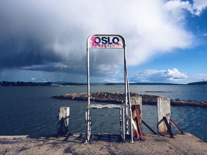 Information sign on beach against sky