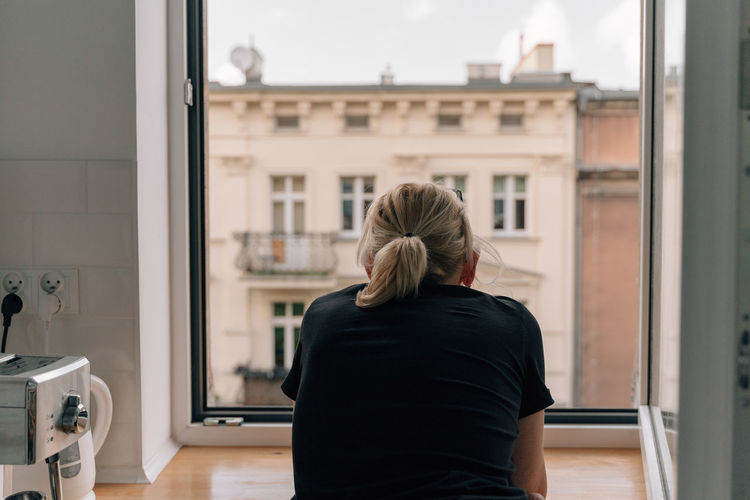 Rear view of woman looking through window