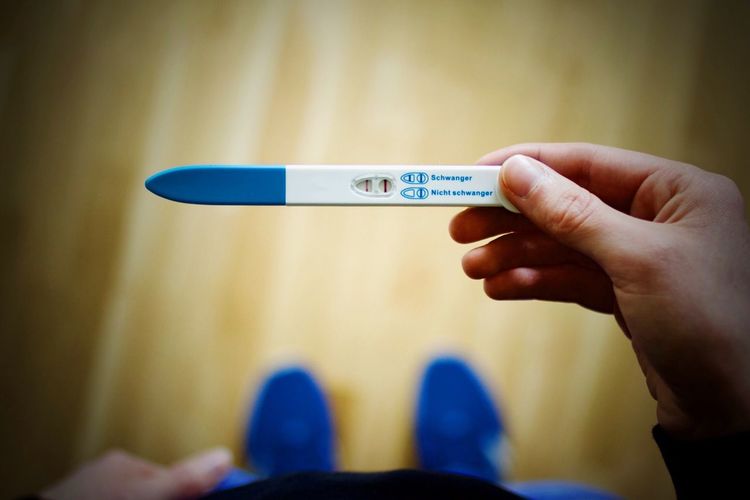 Low section of woman holding pregnancy test