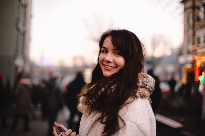 Portrait of smiling young woman standing in city