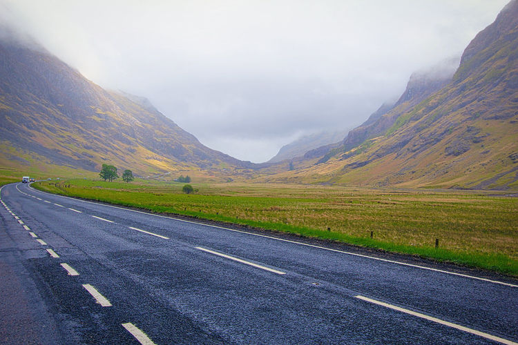 Road leading towards mountains against sky