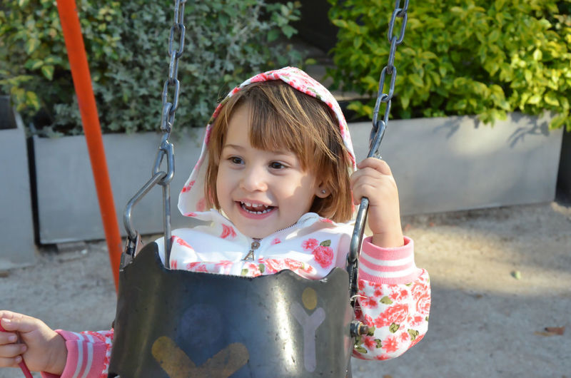 Portrait of young woman swinging at playground