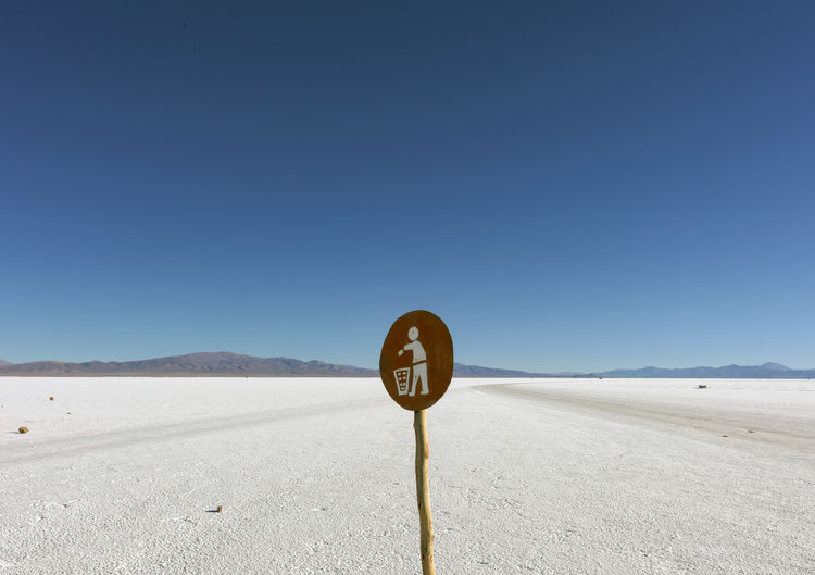 Road sign against clear blue sky salt desert 