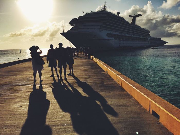People on pier with cruise ship in background
