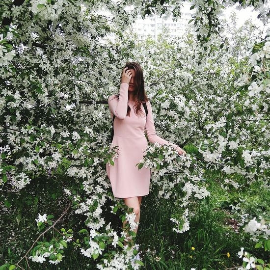 Woman standing by flowers against trees