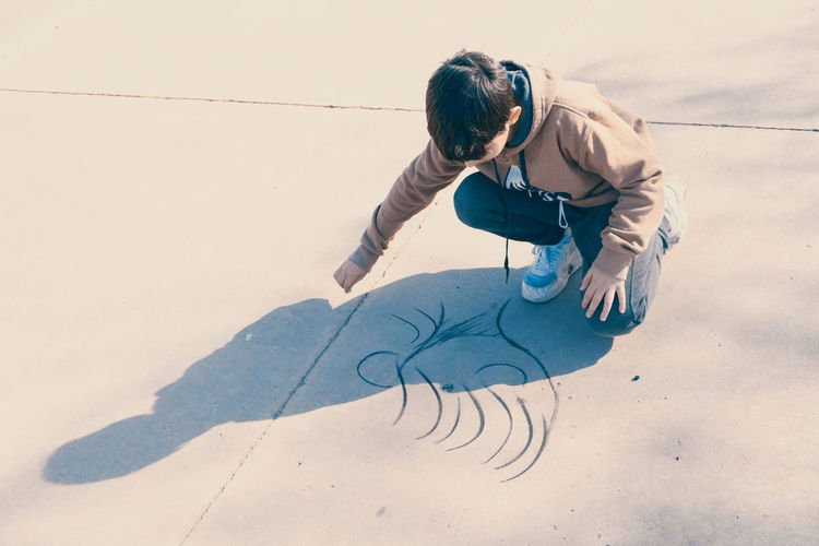 High angle portrait of child drawing in the street