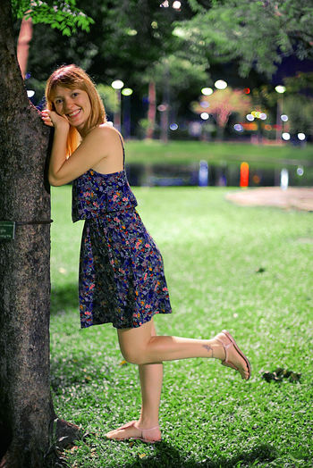 Full length portrait of smiling young woman in park