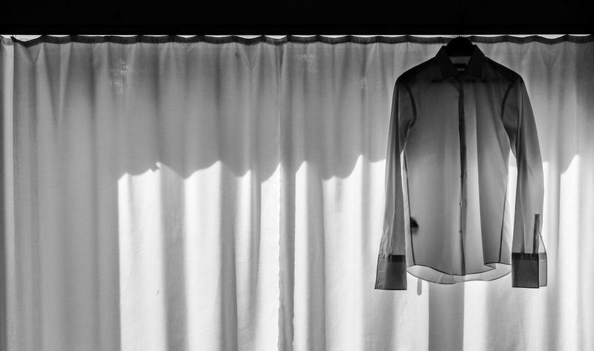 Bridegroom clothing hanging against curtain