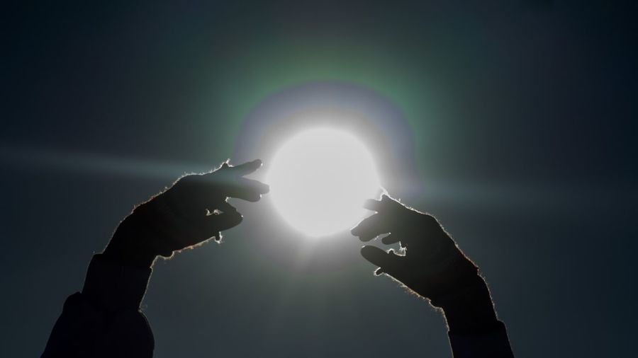 Close-up of hand holding sun over black background
