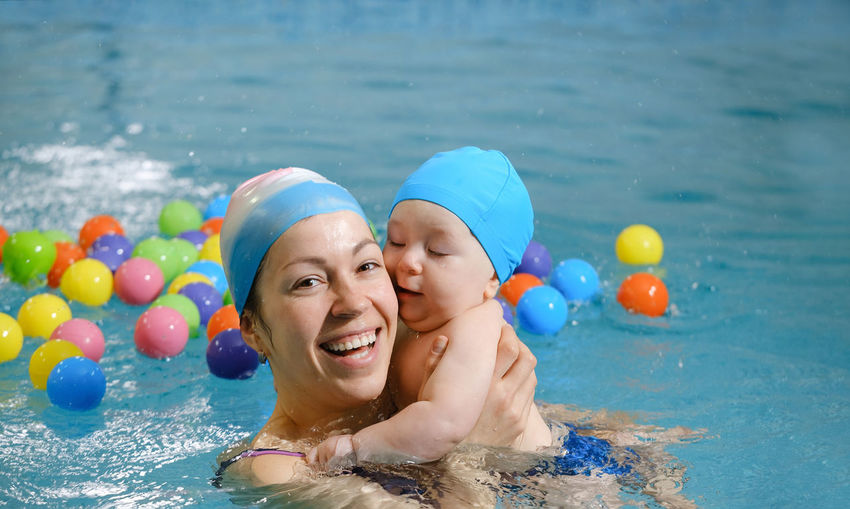 Banner early age swimming in pool. baby boy trained to swim in water. happy child with trainer woman