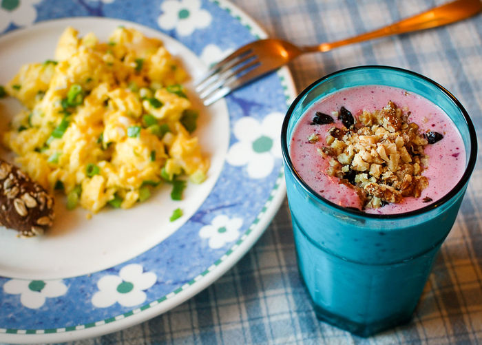 Smoothie and scrambled eggs in plate on table