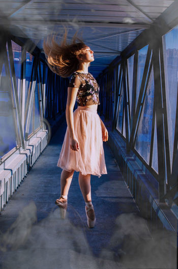 Full length of woman ballet dancing in corridor of building 