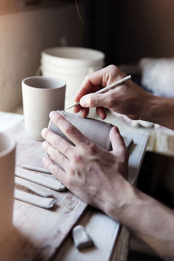 Cropped image of artist carving mug at workshop