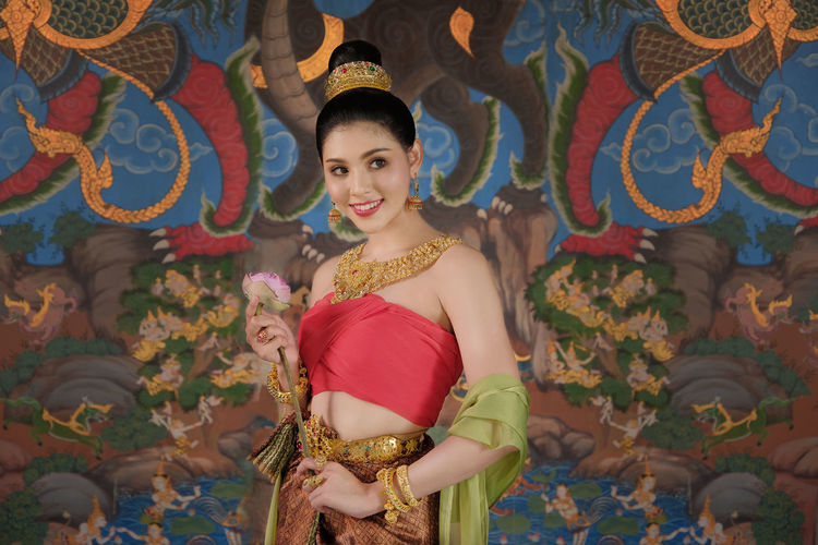 Smiling young woman with flower in traditional clothing