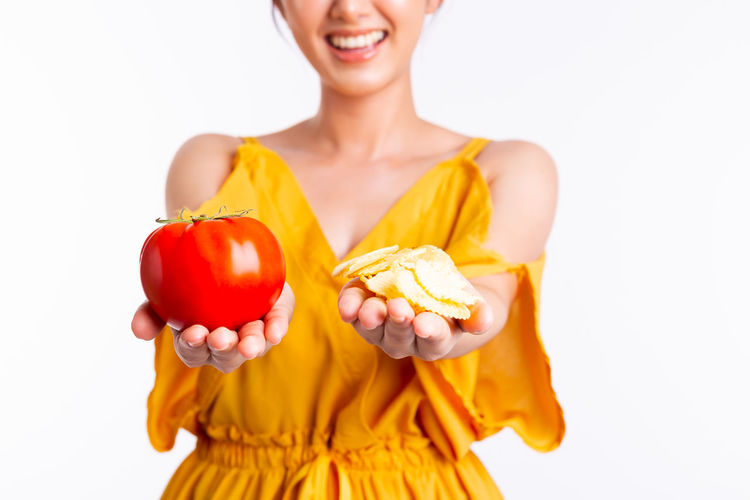 Midsection of woman holding strawberry against white background