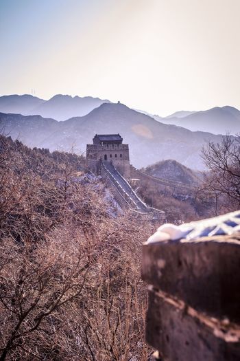 View of tower and great wall of china mountain range against sky with mist across the mountains