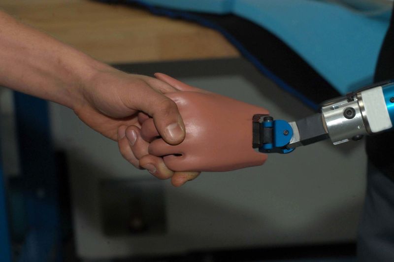 Cropped image of man doing handshake with robotic arm
