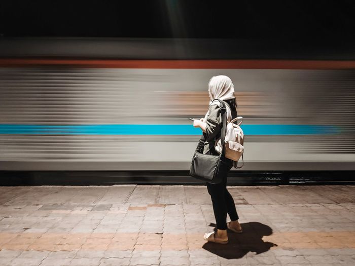 Side view of woman standing on railroad station platform