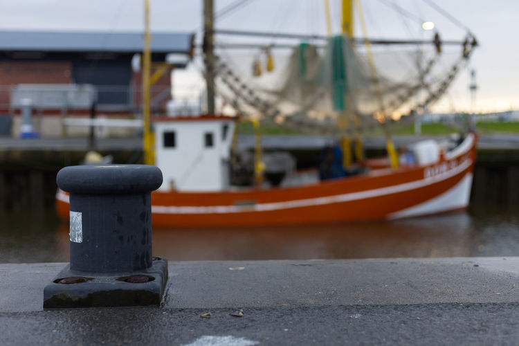 Metal bollard in front of fish trawlers in a port