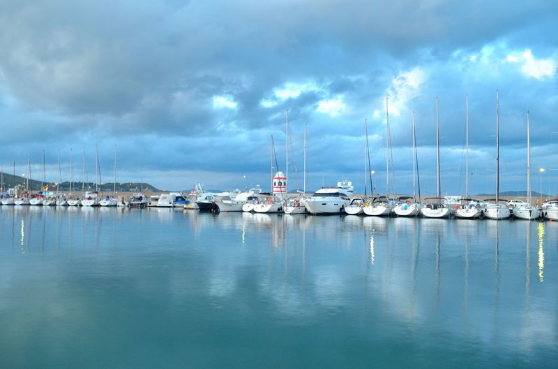 Boats moored at harbor against sky