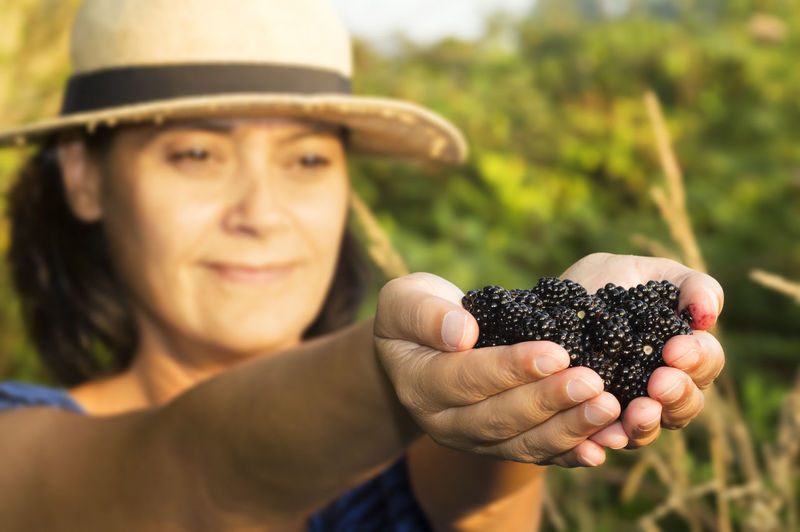 Happy mid adult woman holding mulberries