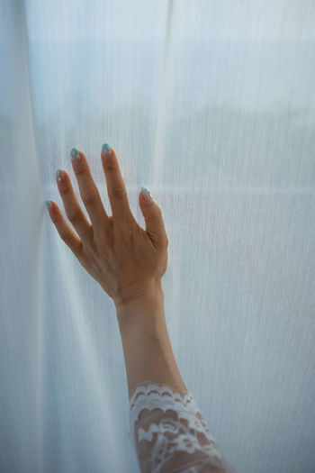 Close-up of woman hand against curtain