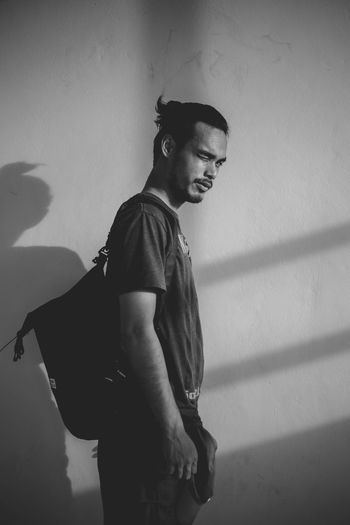Side view of man standing against wall