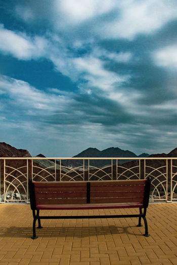 Bench by railing against sky