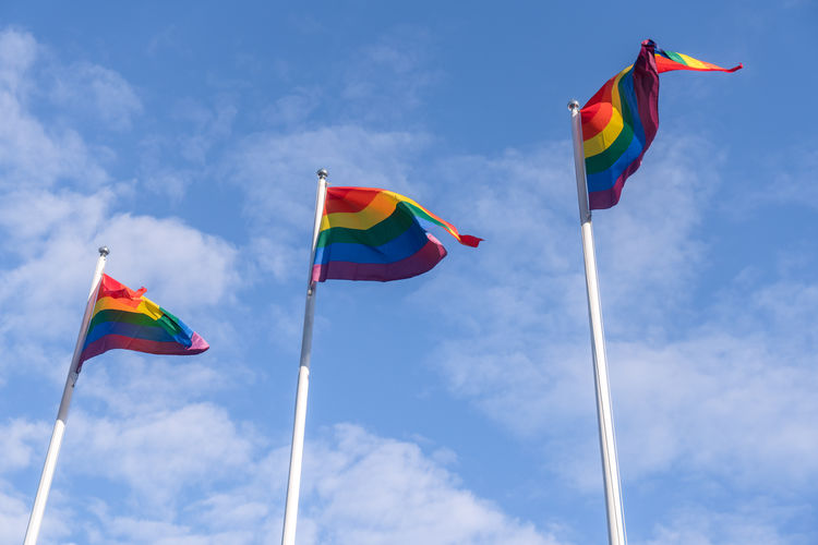 Low angle view of rainbow flags against sky