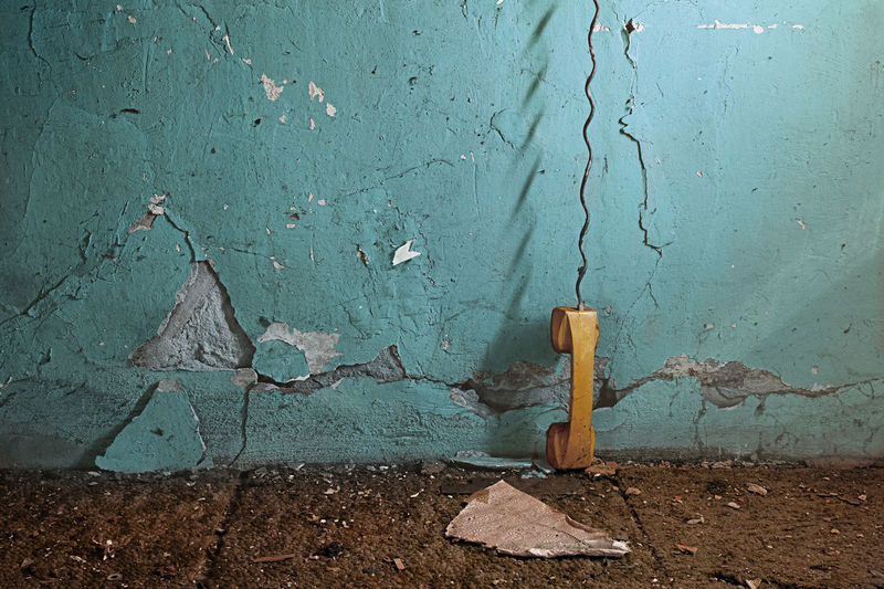 Old- fashioned telephone receiver against weathered blue wall