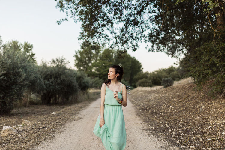 Young woman artist in dress walking along dirt road