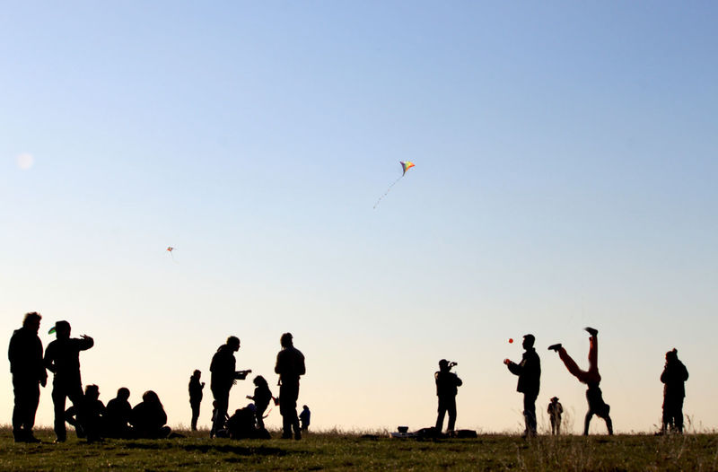 Silhouette people enjoying on field against sky