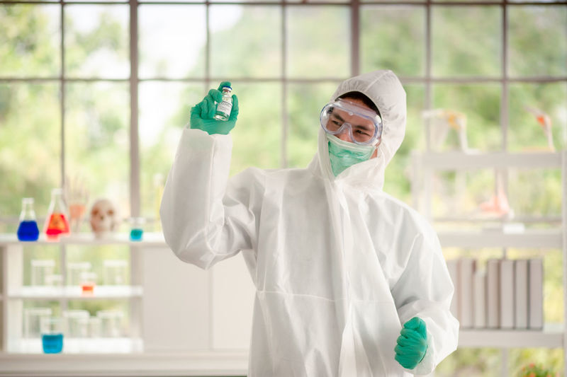 Smiling doctor wearing protective mask standing in laboratory