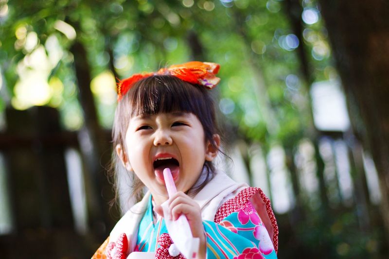 Cute girl wearing kimono while looking away in park