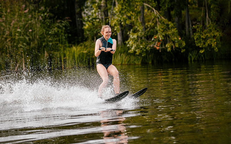 Full length of woman wakeboarding in lake
