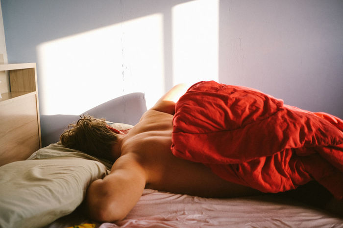 Shirtless man sleeping on bed