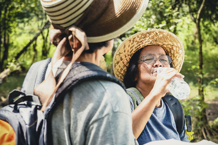 Woman drinking water while hiking with friend