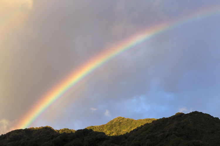 Low angle view of rainbow over mountains against sky