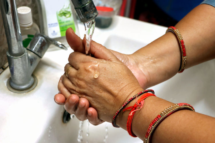 Cropped hands of man washing faucet