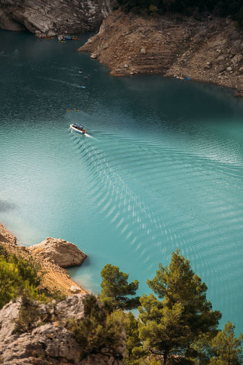 Boat floating and leaving a trail on the turquoise water surface. congost de mont rebei, spain