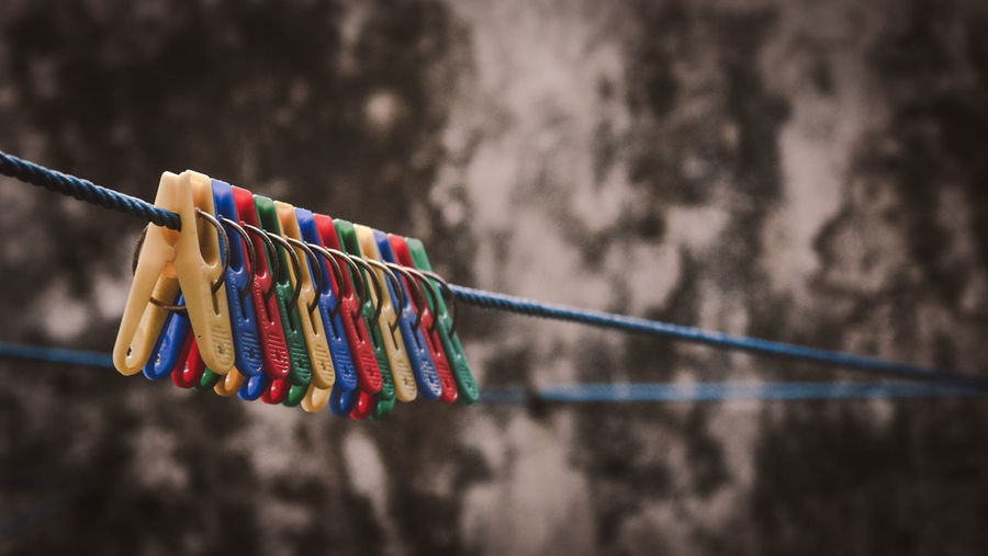 Low angle view of clothespins hanging on rope against sky