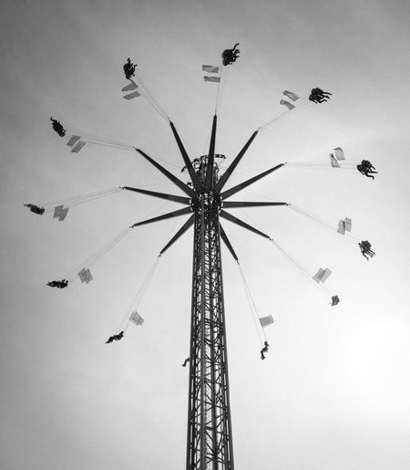 Low angle view of silhouette people on chain swing ride against sky