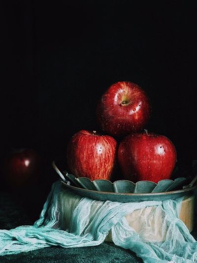 Close-up of apples in basket on table against black background