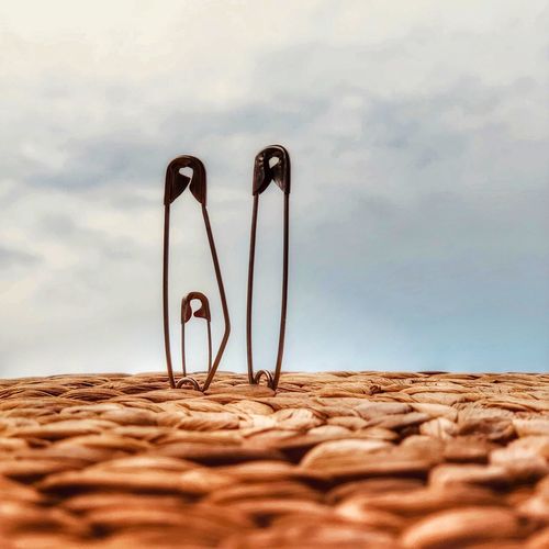 Close-up of safety pins against sky