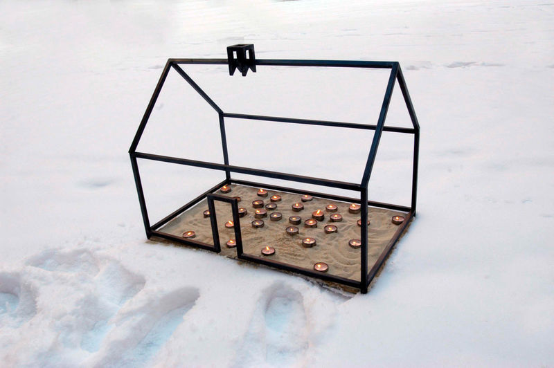 Small glass house with tea lights in it in the snow, thermal insulation in a modern building