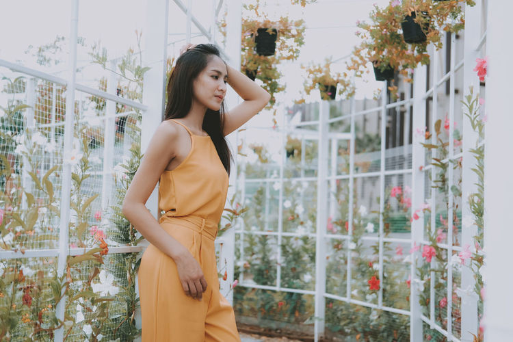 Young woman looking away while standing in garden