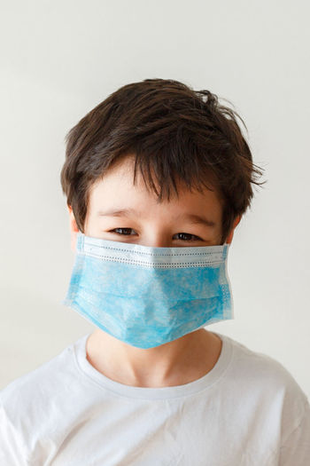 Portrait of asian boy in medical mask against white background
